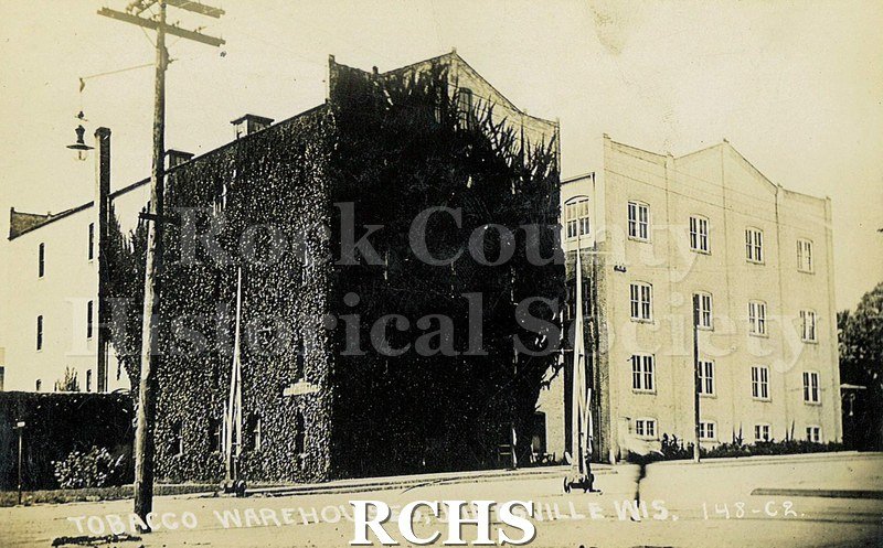 Postcard. Black and white photograph of tobacco warehouses in Janesville.