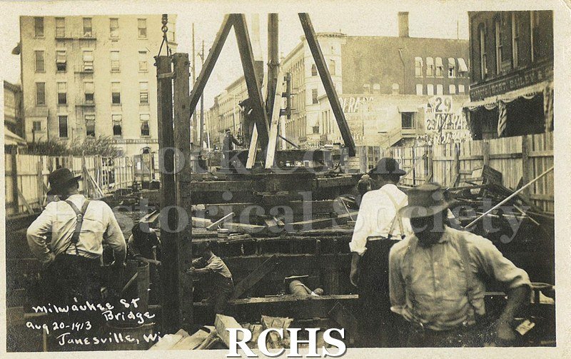 Postcard. Black and white photograph of men constructing the Milwaukee Street bridge in August 1913, possibly as part of the repair effort following the April 1913.