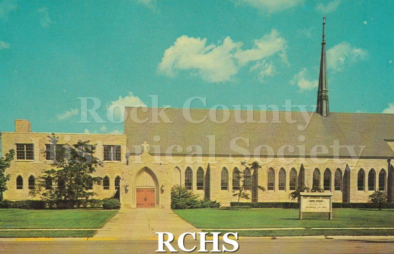 Postcard of First Lutheran Church. Left side with two stories, right side taller, but with peaked roof and steeple.