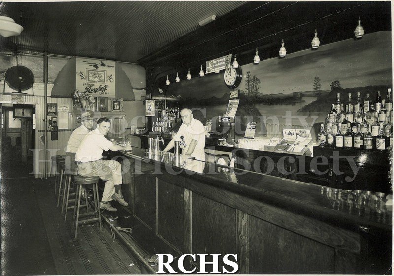 Black and white photograph of Sim's Tavern, located 23 N. Main Street. Owner was Simon Dorn. Pictured are two men resting at the bar's counter.