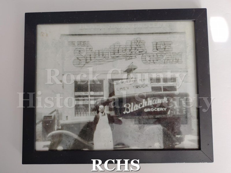 Black and white photograph of an employee at Blackhawk Grocery in Janesville posing in front of a delivery truck.