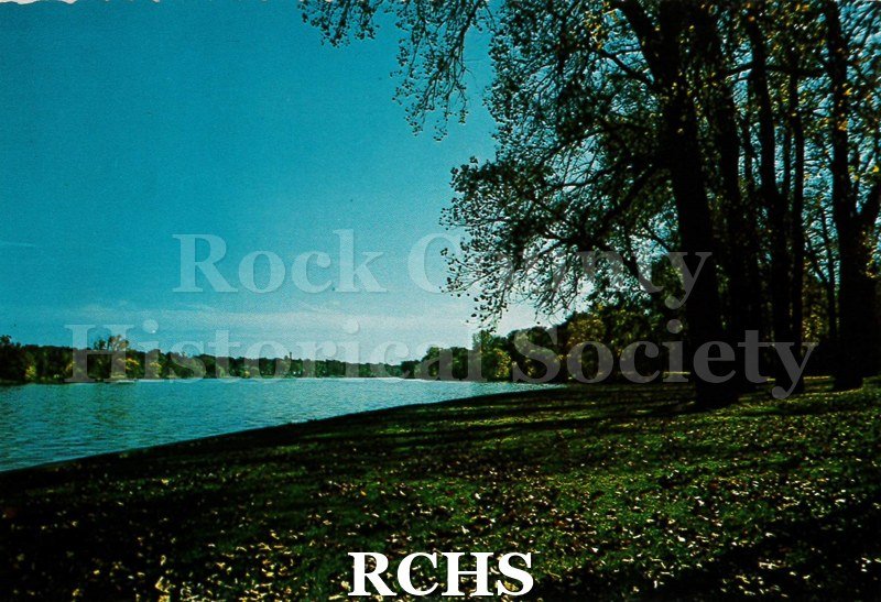 Postcard. color photo of the shoreline along the Rock River at Riverside Park in Janesville.