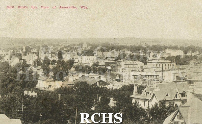 Paper postcard. View of houses and downtown from Court House Hill. "Birds Eye View of Janesville, Wi".
