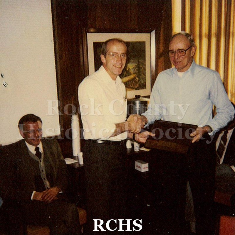 Historic image of Color Polaroid snapshot of Palmer Larson accepting a gift from an unidentified man at the Janesville GM plant.