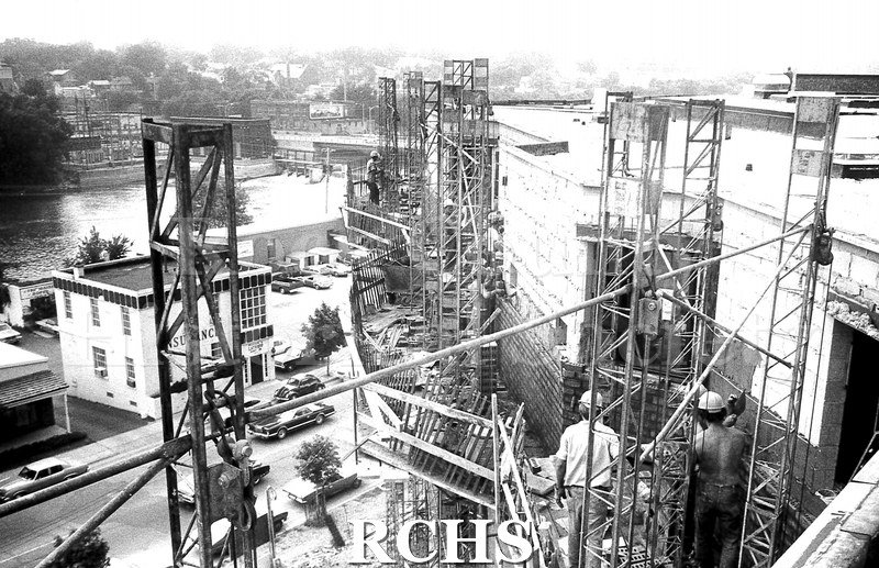 Black and white photograph of Janesville Garden Court Apartments. Shows scaffolding with two men standing on a platform.