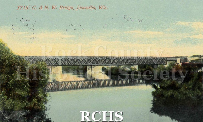 Postcard of C. and N.W. Bridge over the river with reflection. Trees and bushes on both sides.