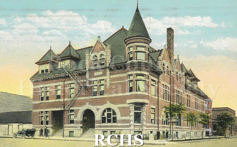 Y.M.C.A. Building, Janesville, Wis.. Front of postcard shows a color illustration of a large brick building on a street corner. "Y.M.C.A.