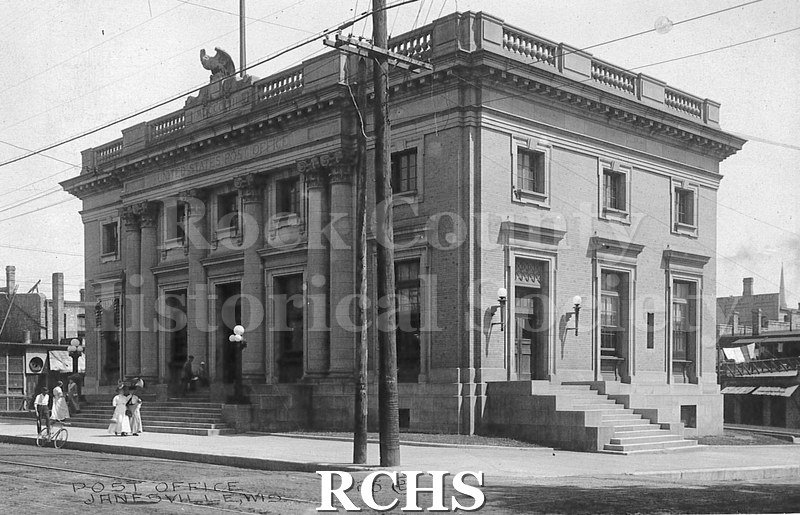 Postcard. Black and white photograph of the exterior of the post office in Janesville. Addressed to Catherine McCullock in Janesville. Postmarked 30 July 1914.