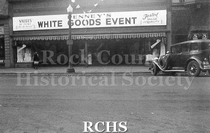 Black and white photograph of sign above Penney's store. It reads: "Penney's White Goods Event" and "Values" and "Trusted Value and Quality".