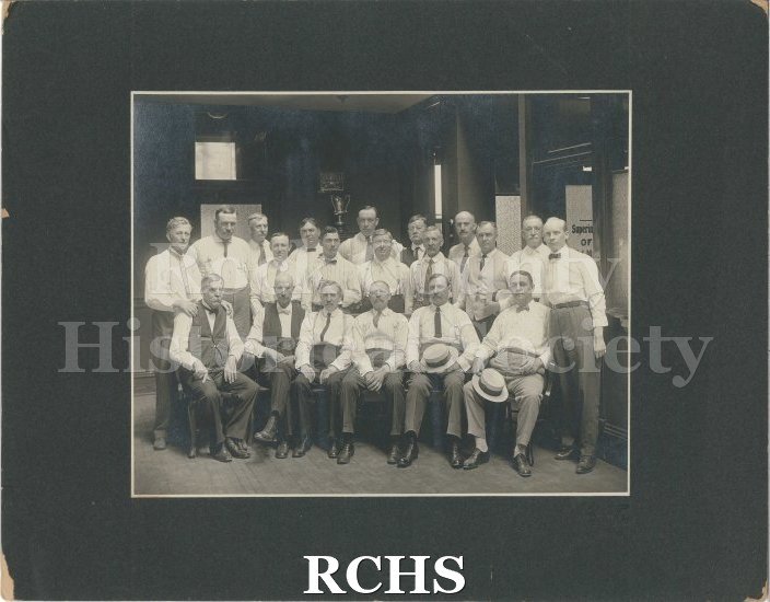 Black and white photograph of Janesville Machine Company workers: 20 men wearing white collared shirts, ties, slacks, and business shoes. Three have vests.