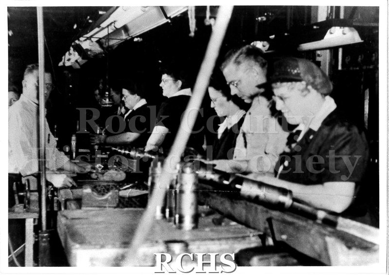 Black and white photograph of men and women working on a line at the Janesville Fisher Body factory, in 1944.