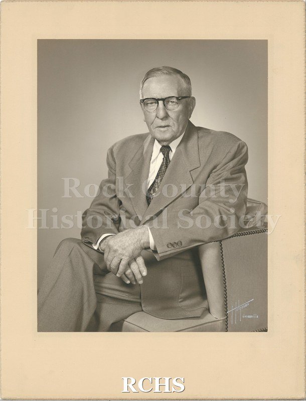 Black and white studio portrait of Joseph Albert Craig. Craig is an older man, wearing a suit and tie. He has short grey hair and glasses.