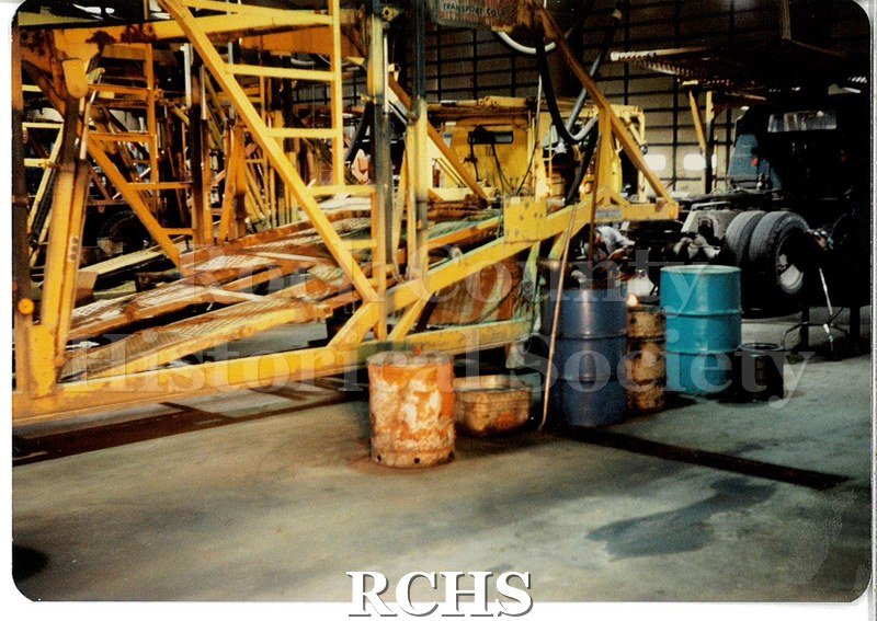 Color photo of the minor repair bay at JATCO (Janesville Auto Transport Co.) A car transport trailer (painted yellow) takes up most of the frame.