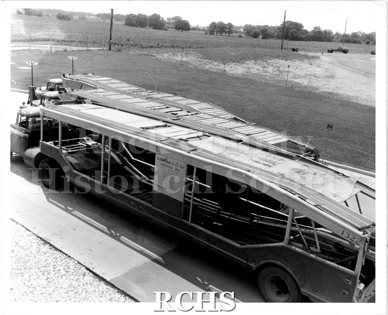 Black and white photograph of W. R. Arthur transport trailers ready to be loaded up. Three trucks are lined up outside.
