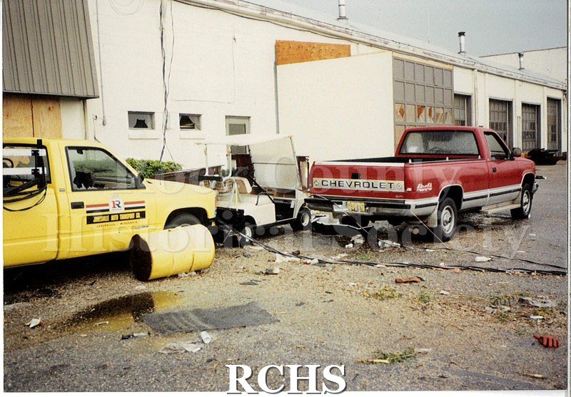 Color photo of the damage to the Janesville Terminal from the 1991 tornado. Shows damage to the exterior of the building as well as to some cars.