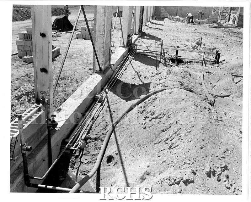Black and white photograph of piping to tanks under the floor of the weld shop in the K building.