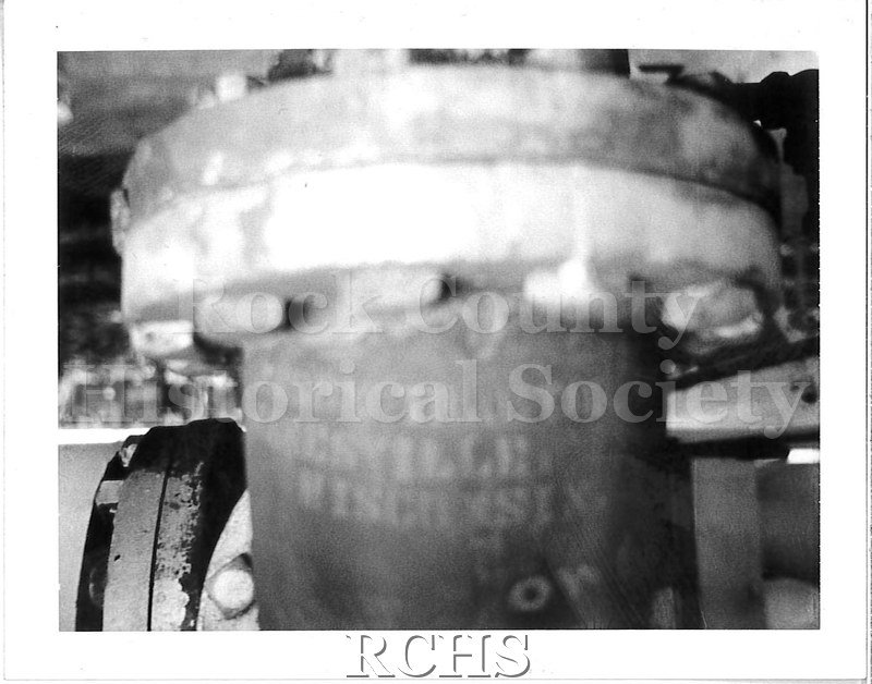 Historic image of Black and white Polaroid of a machine part (engine?). The part is out of focus and close to the flash.