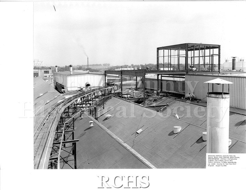 Black and white photograph of men working on the roof of a building under construction. On bottom: "Alterations-Additions, Janesville Plant, Wis.