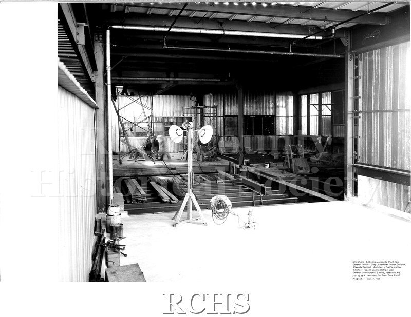 Black and white photograph of the interior of the construction. There is a light on a pole in the front of the photograph.