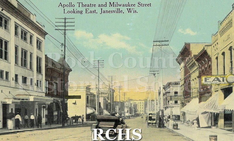 Postcard. Tinted image of pedestrians and traffic of Milwaukee Street in Janesville, looking east of the Apollo Theater.