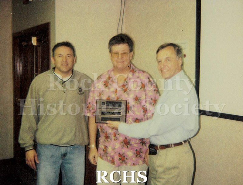 Historic image of Color polaroid of Lyle Ackerman receiving an award while Mike Sheridan, UAW Union President, and Gary Malkus, Janesville GM Plant Manager, c. 2000.