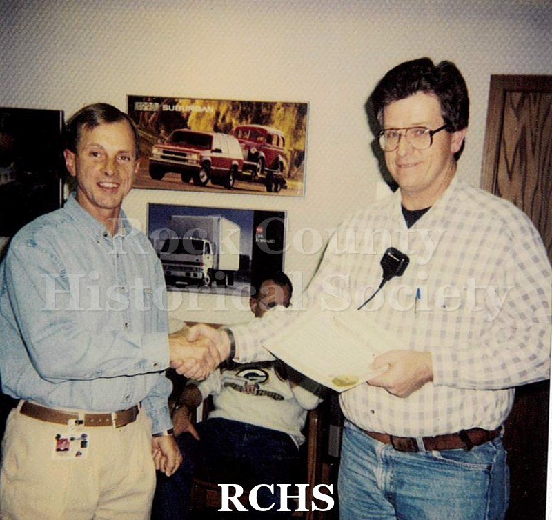 Historic image of Color Polaroid snapshot of Lyle Ackerman receiving an unknown award from a supervisor at the Janesville GM plant.