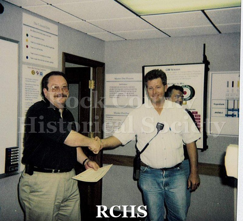 Historic image of Color Polaroid snapshot of Lyle Ackerman receiving an award certificate from an unidentified supervisor at the Janesville GM plant.