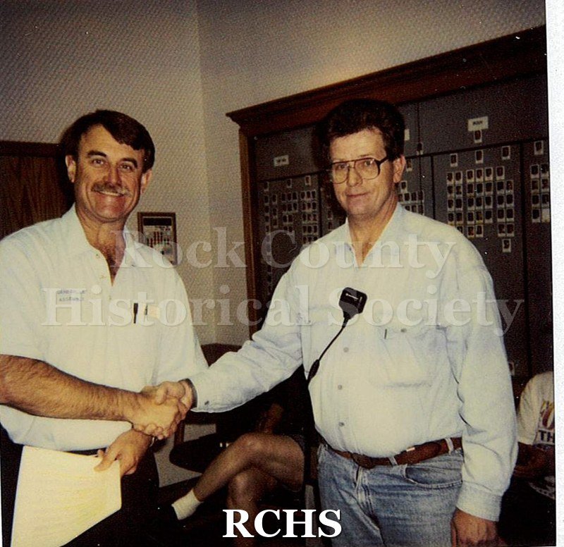 Historic image of Color Polaroid snapshot of Lyle Ackerman receiving an award certificate from an unidentified supervisor at the Janesville GM plant.