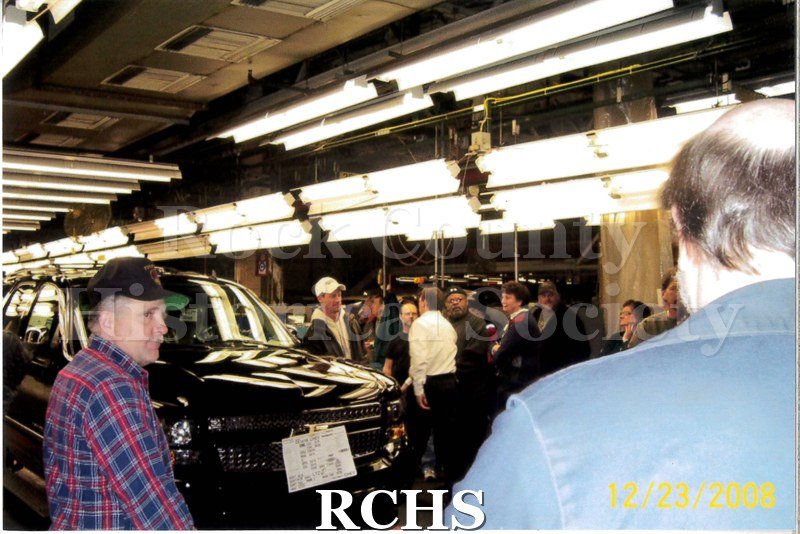 Digital color photo of employees at Janesville General Motors standing around the last car to be made at the plant.