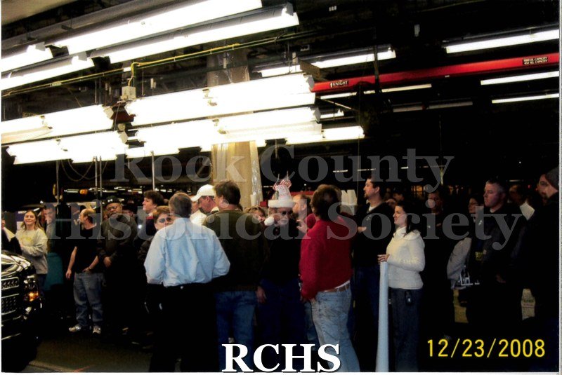 Digital color photo of employees at Janesville General Motors gathered around the final car to be assembled at the plant.