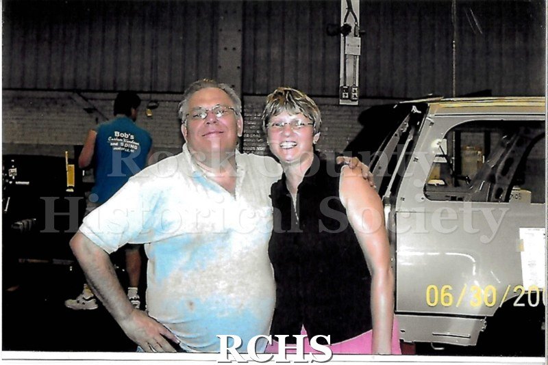 Digital color photo of employees at Janesville General Motors posing on the line. Two people stand close to the camera.