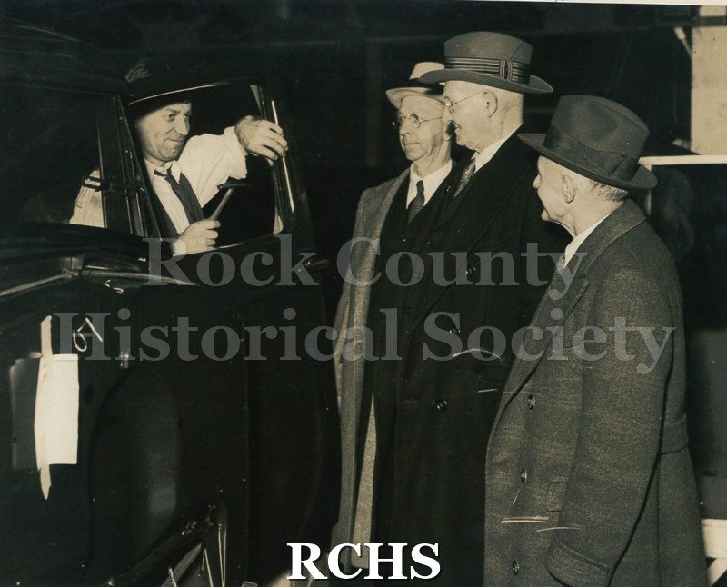 Black and white photograph of a group of men observing the assembly line at the Baltimore GM plant. Thomas Butters is included in the group.
