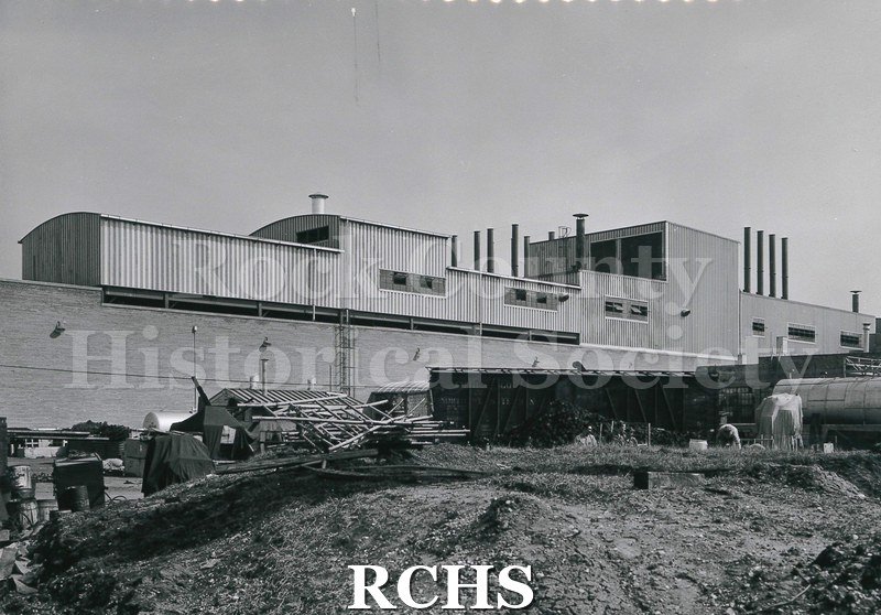 Black and white photograph of men working on the outside of the addition. On bottom: "Alterations-Additions, Janesville Plant, Wis.