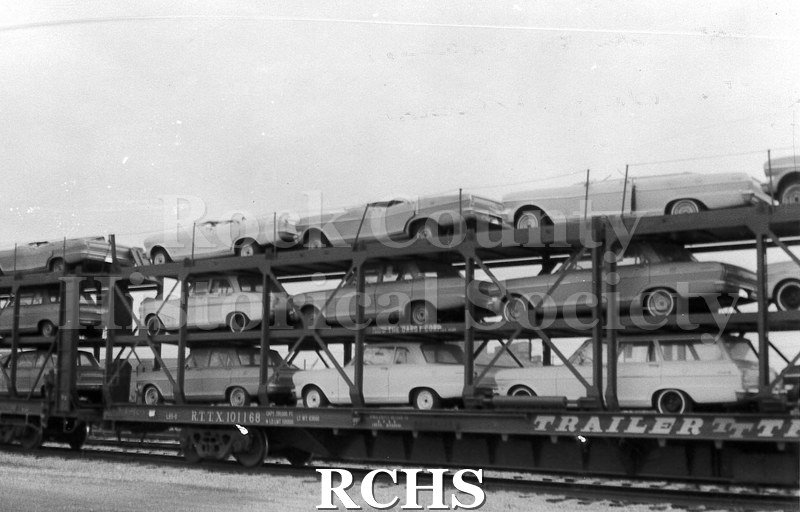 Black and white photograph of cars from the Janesville GM plant loaded on to a railroad car.