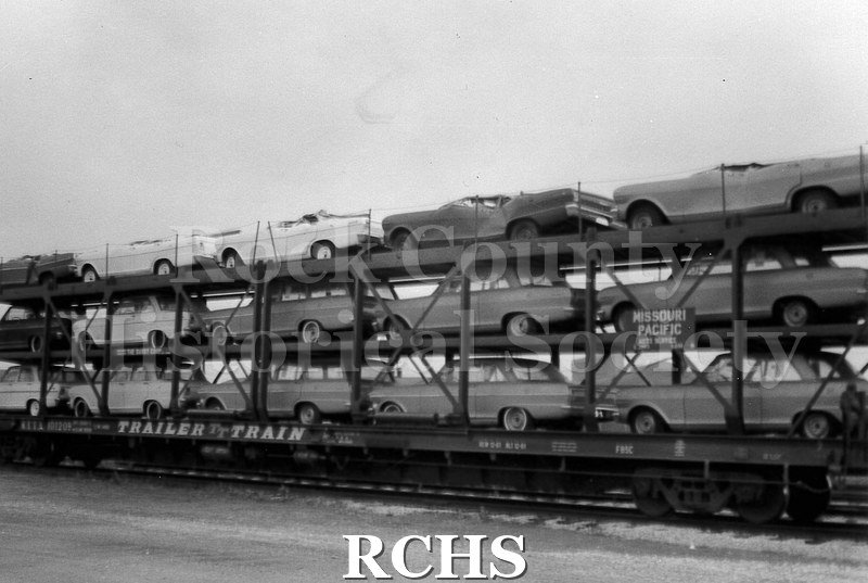 Black and white photograph of cars from the Janesville GM plant loaded on to a Missouri Pacific railroad car.