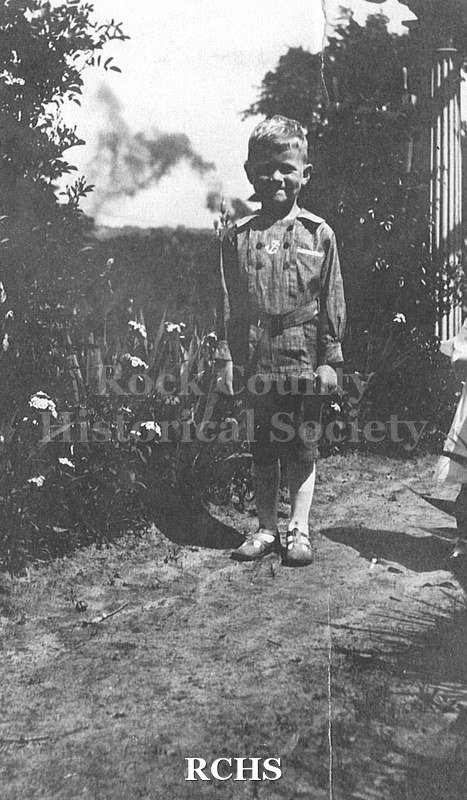 Black and white photograph of Charles N. Tallman as child (about 5 years old) dressed in sailor jacket, knickers, socks and sandals. Big grin on his face.