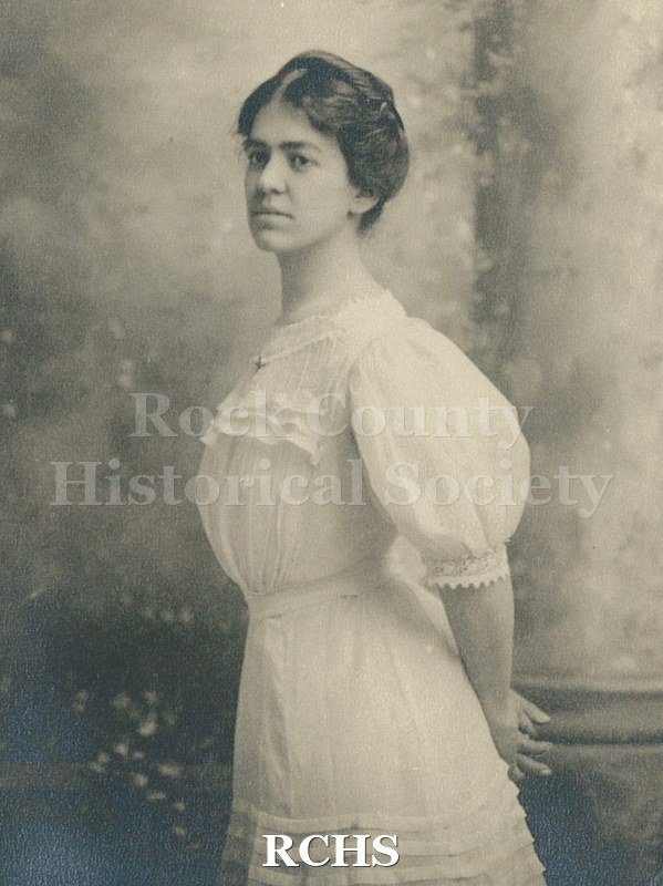 Black and white photograph of Clara May Felton Tallman in 3/4 profile. Dressed in light colored dress with round neckline, puff sleeve to just below elbow length.