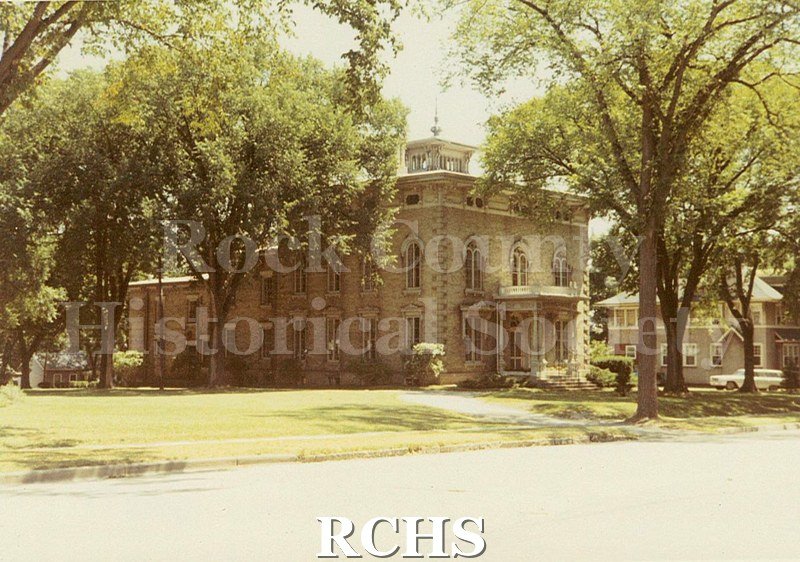 Colored photograph of the Tallman House from across the road. Trees are leafed out.