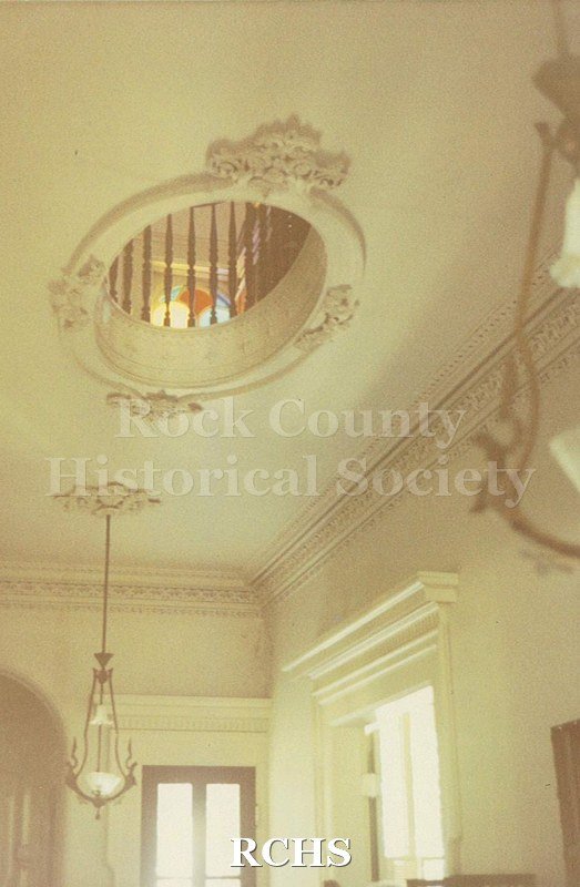 Colored photograph of the Tallman House second floor hallway with open window in floor.