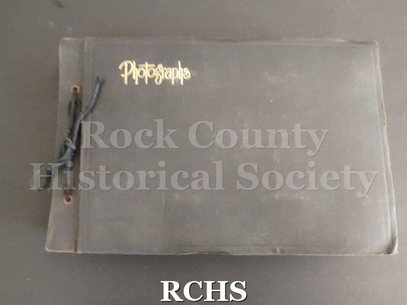 Photo album. Black canvas album with "Photographs" on cover in gold. Ties with a black string and has black paper pages.