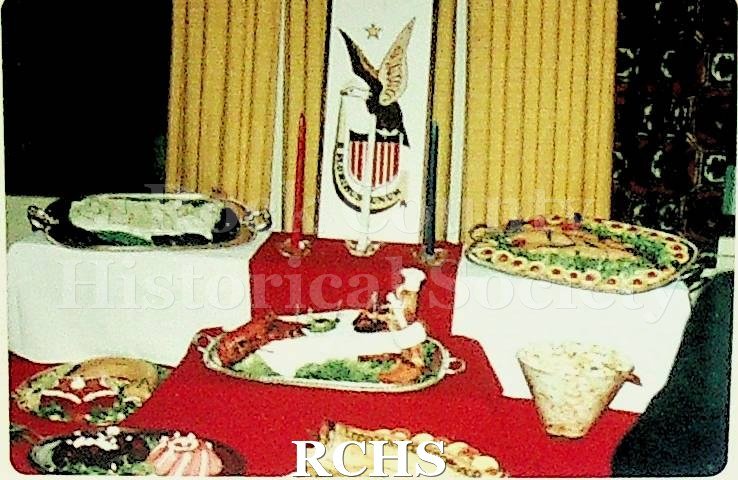 Color photo of an elaborate buffet created by Frank Howery for an unknown GM company event. There are red, white, and blue candles and a banner with the U.S.