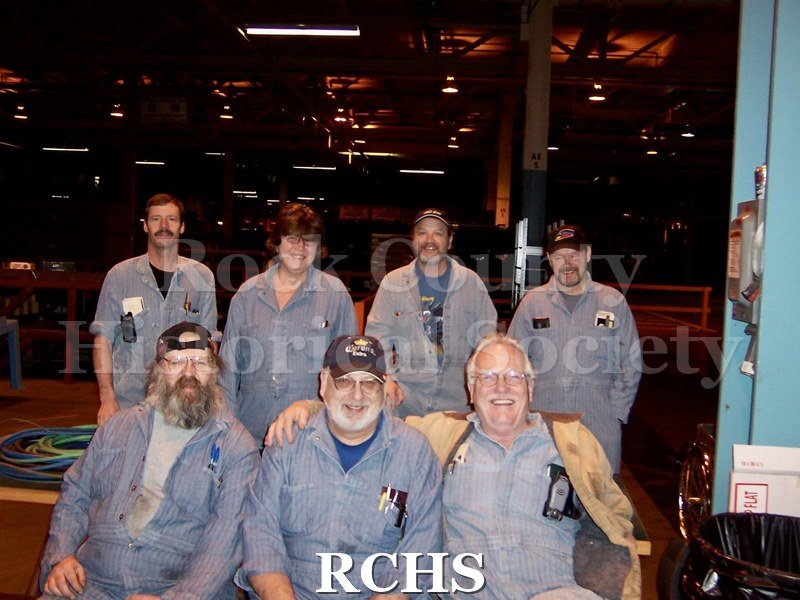 Color photo of Eric Johnson (standing, back left corner) with co-workers at the Janesville General Motors plant.