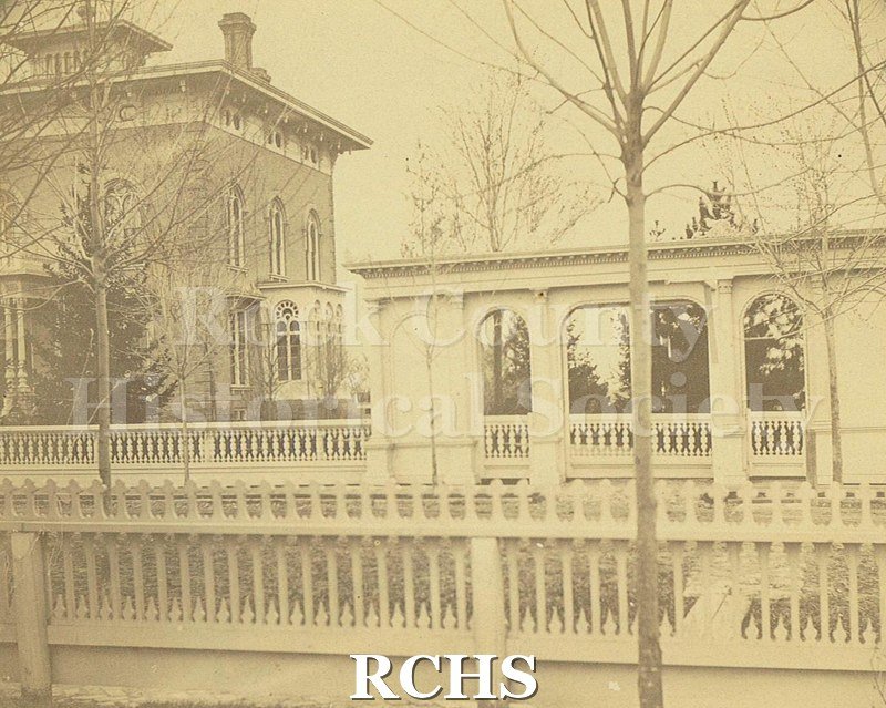 Black and white photograph of front and conservatory side of the Tallman House showing the front fence and gate entry.