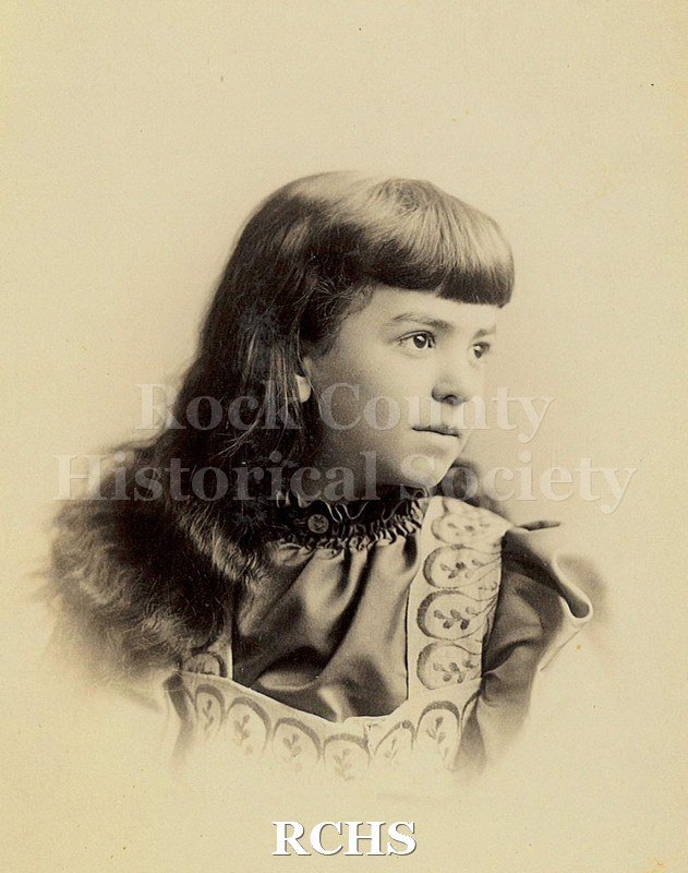Black and white photograph of May Felton as a young girl in 3/4 profile looking to her left. Long hair with bangs.
