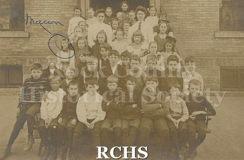 Tinted photo of Central School, Janesville. Shows a group of school kids and their teachers outside of the school building.