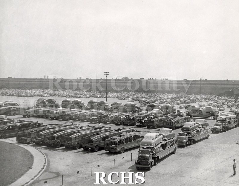 Black and white photograph of W.R. Arthur transporters loaded with a large factory behind them.