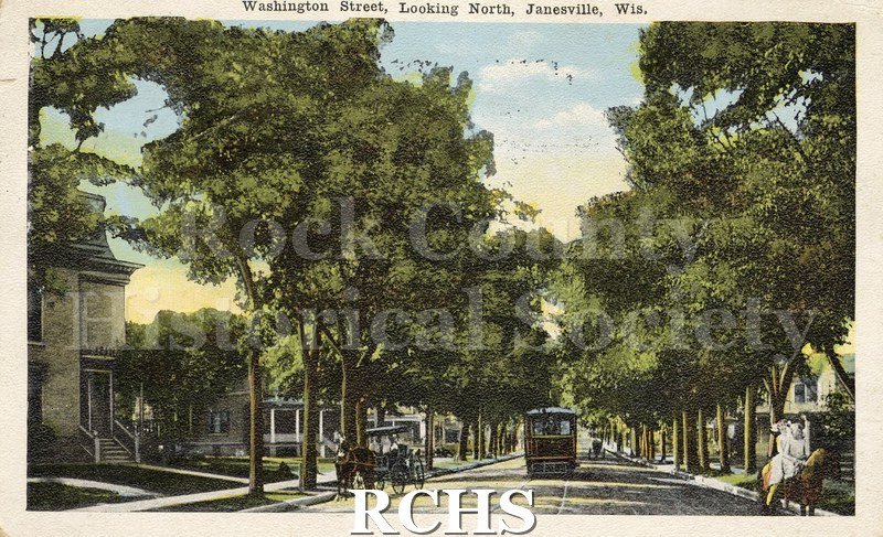 Postcard. Tinted image of a trolley and carriages on Washington Street in Janesville.