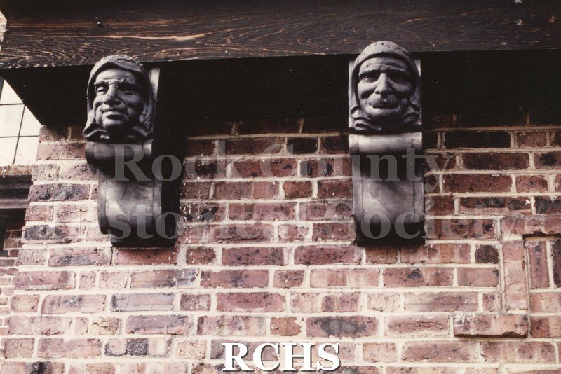 Colored photograph of 200 S. Garfield, Janesville, WI. Shows a two-story house. Shows two gargoyles on the brick wall.
