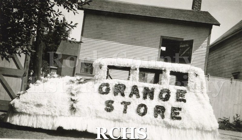 Black and white photograph of a 1928 Buick is decorated with white tissue. The words: "Grange Store" are shown in black.