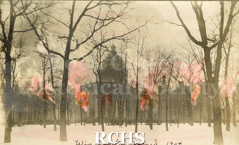 Black and white photograph of Wisconsin Capitol. This is a drawing of a building burning. There are trees in the foreground. On bottom: "Wis. Capitol burned 1904".